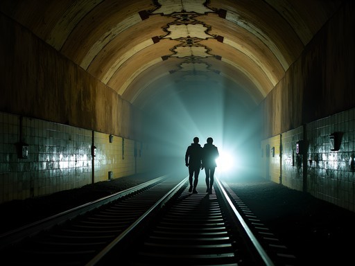 Couple exploring abandoned City Hall subway station with flashlights