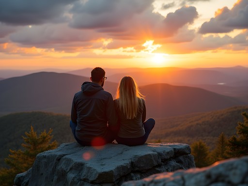 Couple sitting on Mount Hunger's rocky summit watching sunset over Green Mountains